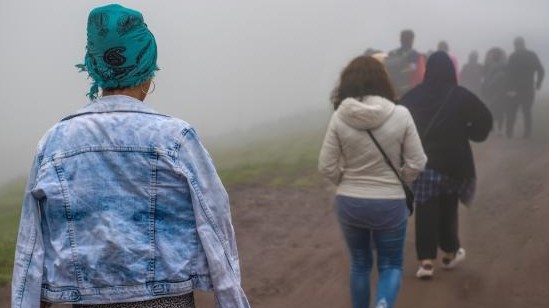 line of people walking on a dirt path with their backs to the camera