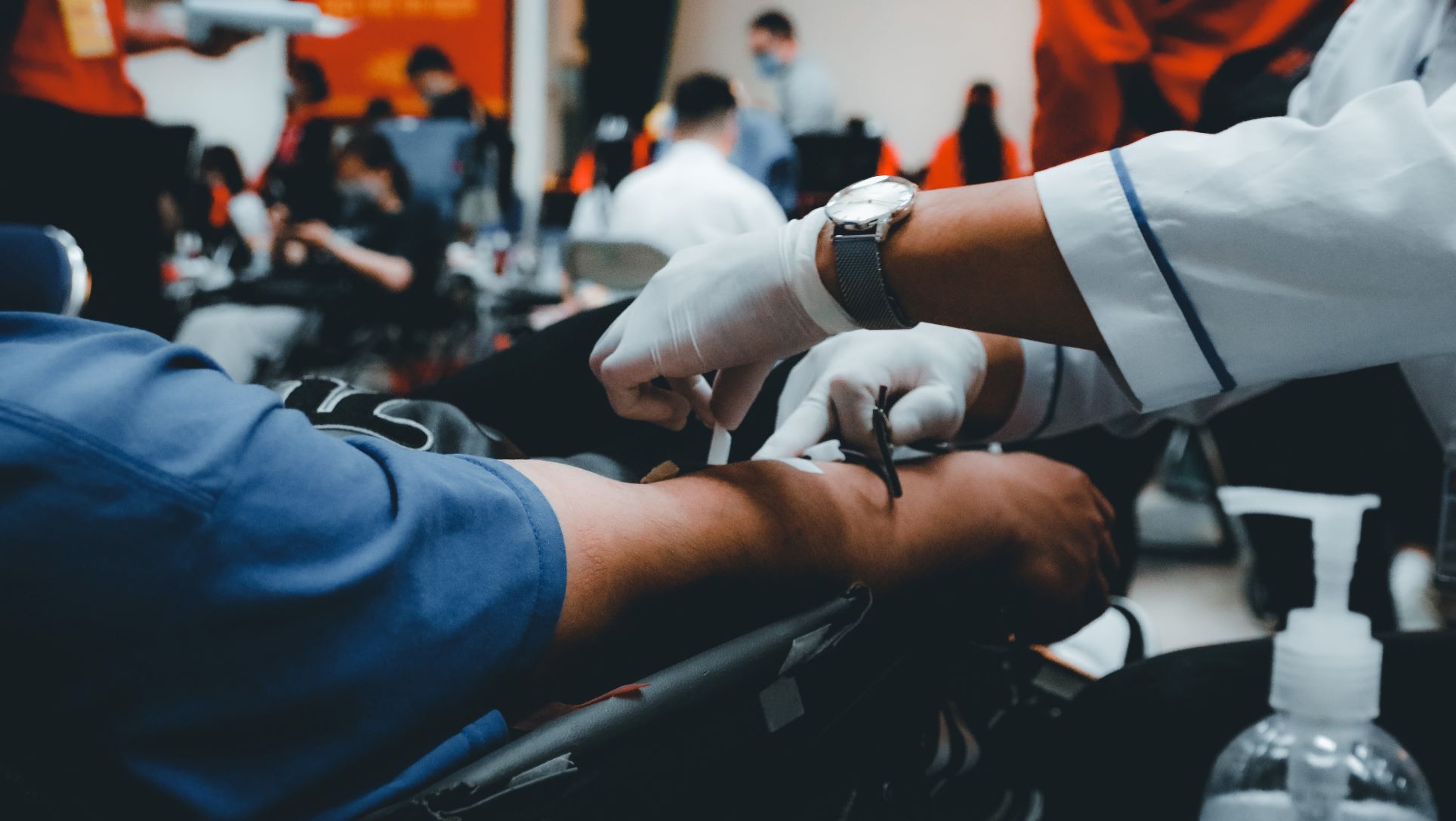 Person with gloves cleaning arm to draw blood at blood drive