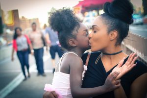 Woman of color kissing daughter on cheek