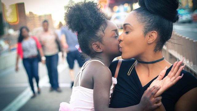 Woman of color kissing daughter on cheek