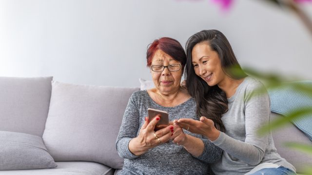 Daughter and mother sitting together looking at a phone.