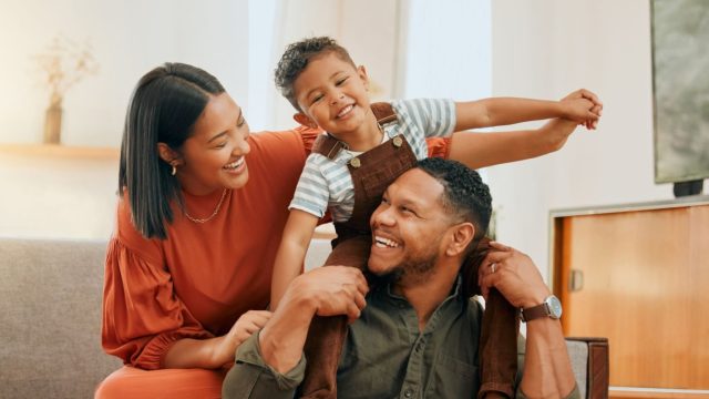 Loving Black family bonding with their son while playing fun games on the sofa at home.