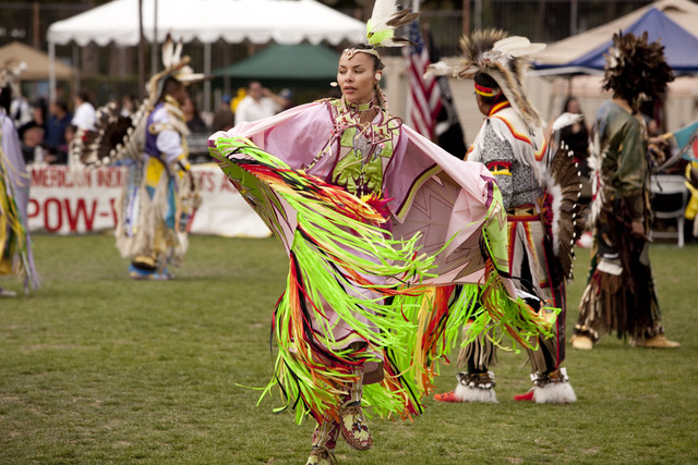 Native American woman in traditional dress dancing.