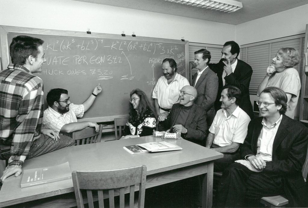 The Environment and Behavior Program in May 1994. Members surround a table with a chalkboard in the background.