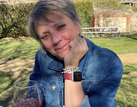 Denise Porchetta at picnic table with glass of wine