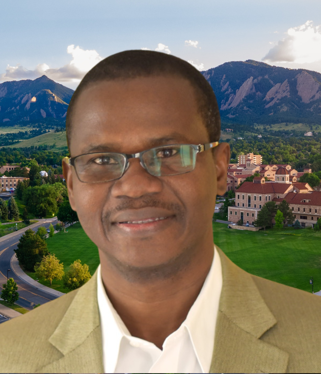 Alex Ezeh wears a tan jacket and glasses. Behind him, a view of the CU Boulder campus and Boulder Flatirons.