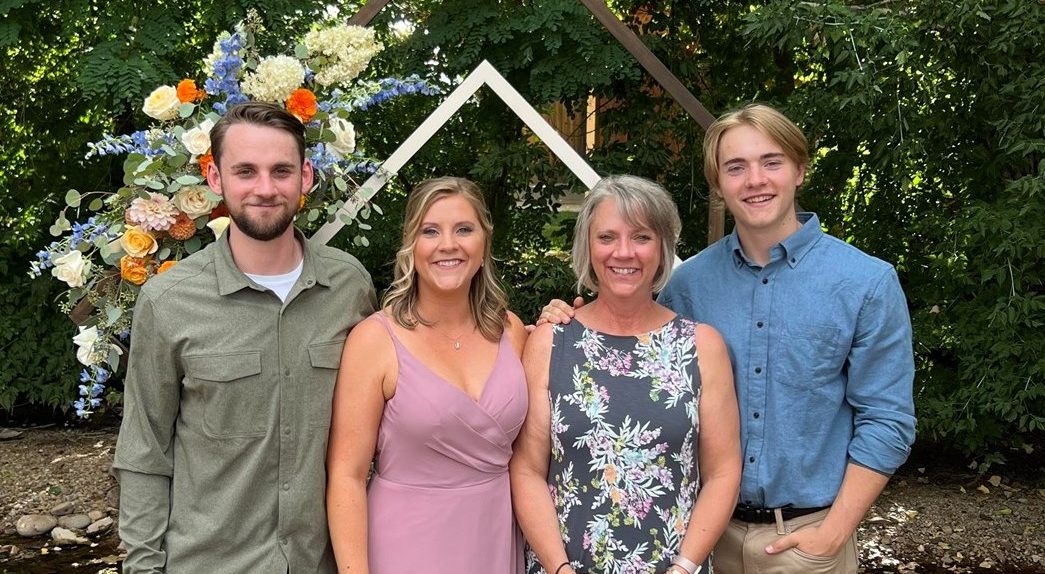 Denise Porchetta with her children, Vincent (left), Danielle (second from left) and Dante (right) stand for a family photo amongst a canopy of trees.