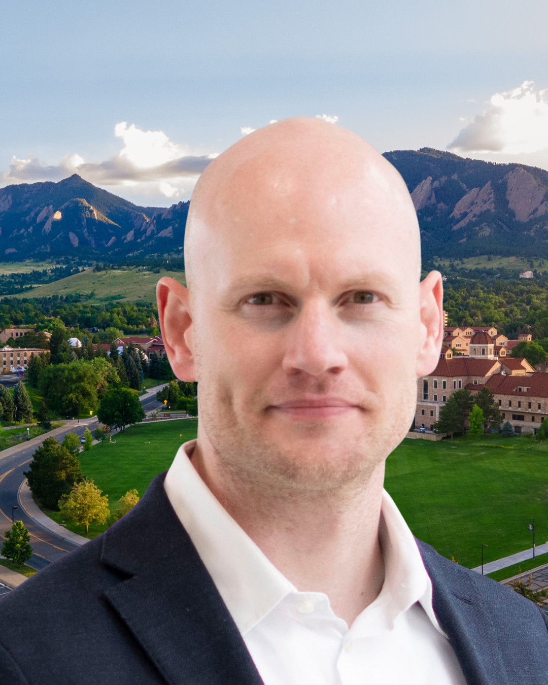 James Hensley wears a blue jacket and white collared shirt. Behind him, a view of the CU Boulder campus and Boulder Flatirons.