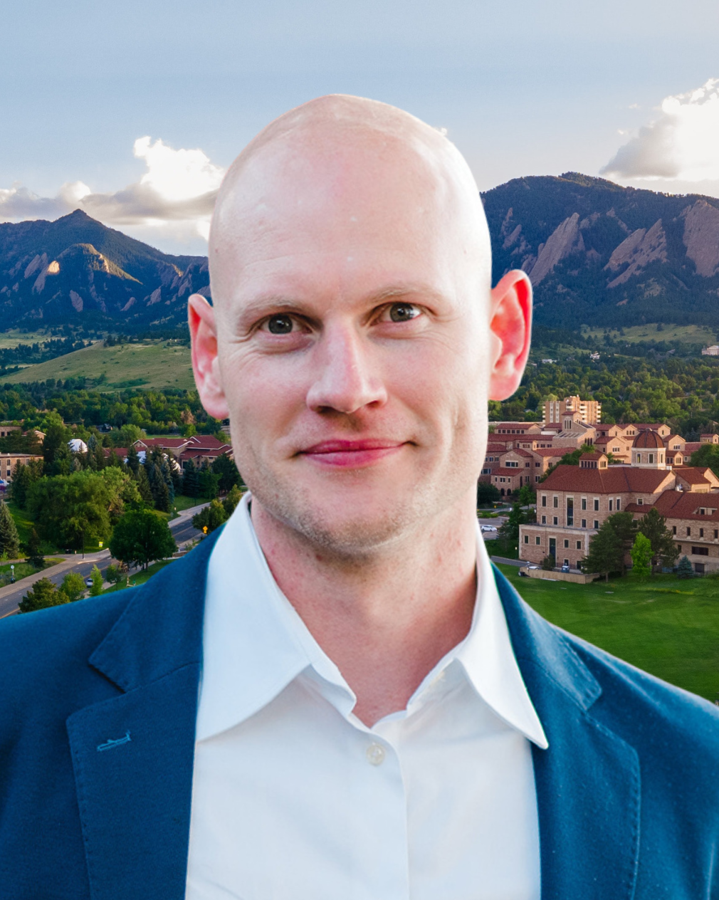 James Hensley wears a blue jacket and white collared shirt. Behind him, a view of the CU Boulder campus and Boulder Flatirons.