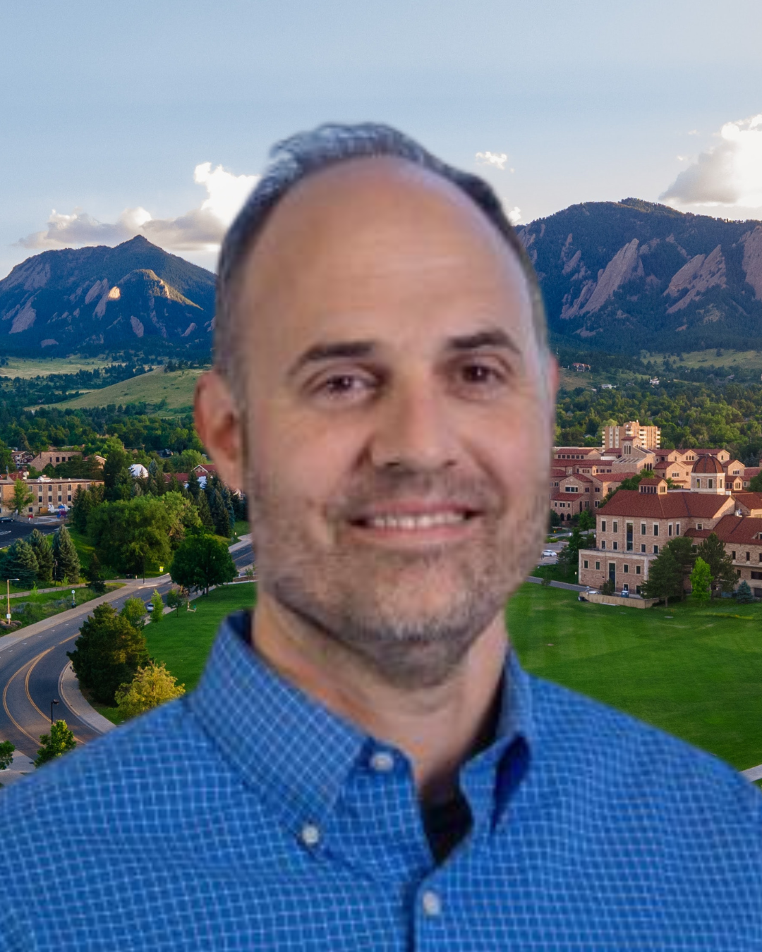 Stephen Billings wears a blue button down shirt. In the background, the CU Boulder campus with view of the Boulder Flatirons.