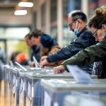 A line of people place their ballots to vote.