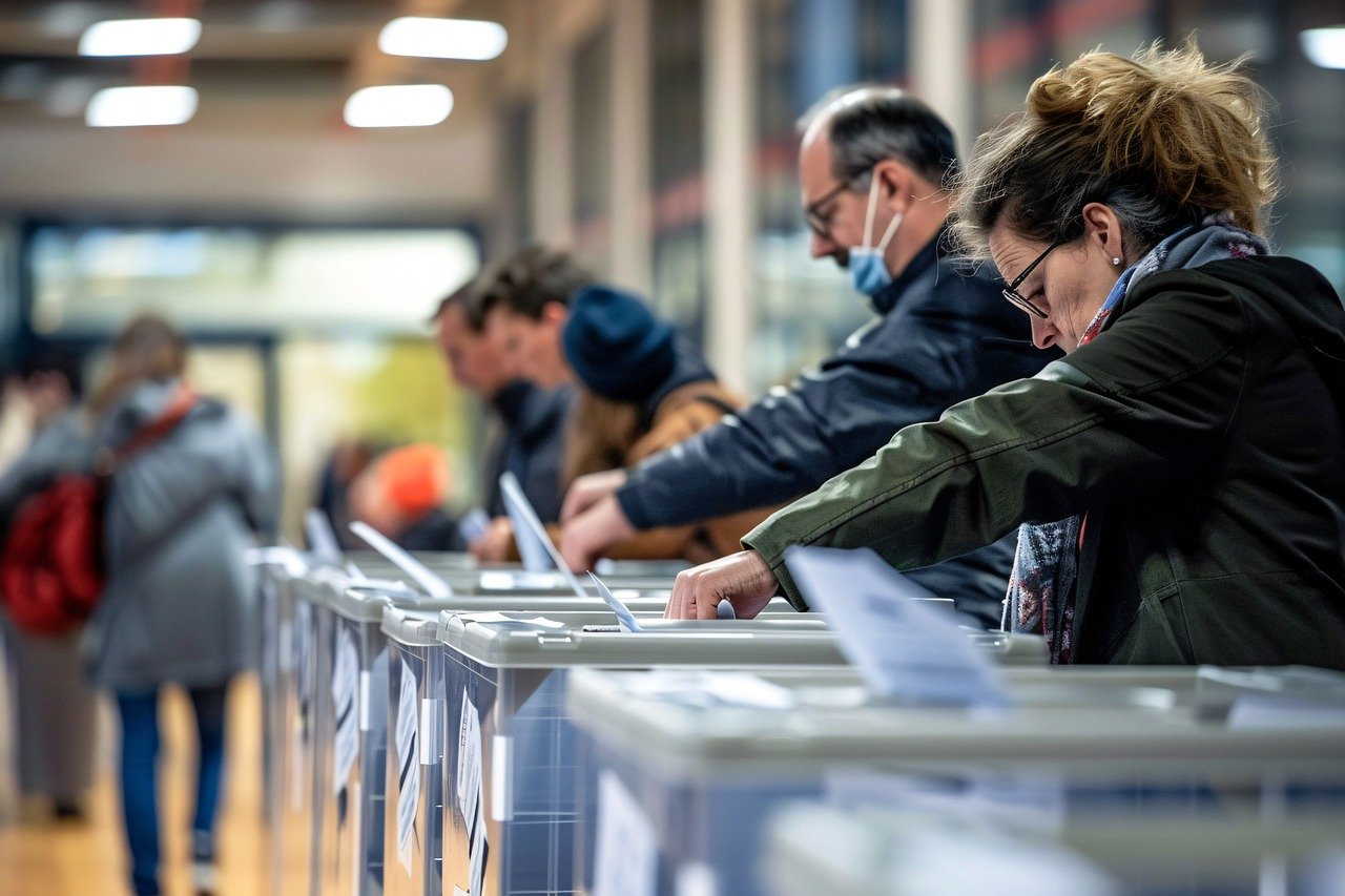 A line of people place their ballots to vote.