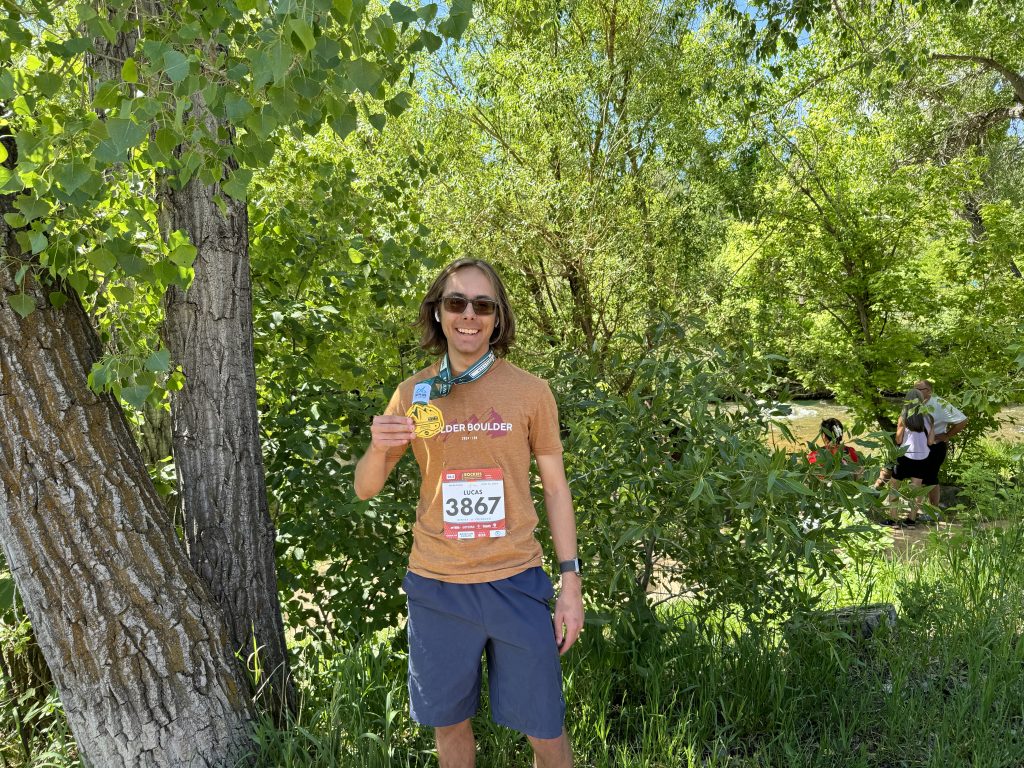 Lucas stands showing off a metal at a marathon run. Lucas ran a sub 3-hr marathon over the summer!