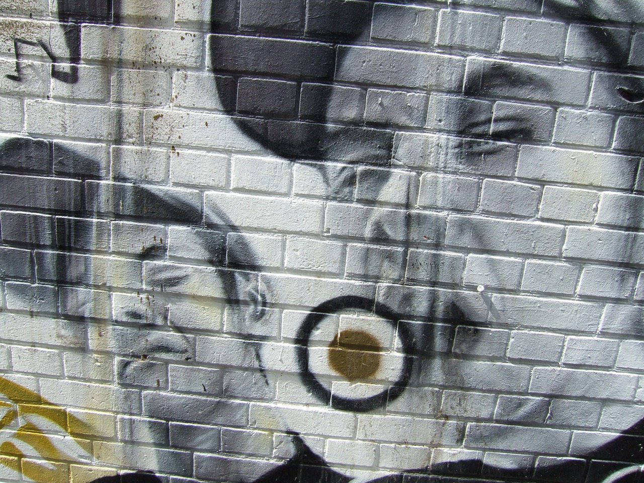 Graffiti image of two boys wearing caps adorns a brick wall. A target is pictured in the middle.