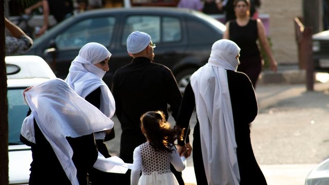 A family looks at oncoming traffic before crossing the street in Syria.